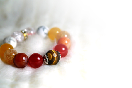 Tiger eye and various quartz lucky stone bracelet in red and white tone on white wool texture background and have some space for write wordingの写真素材