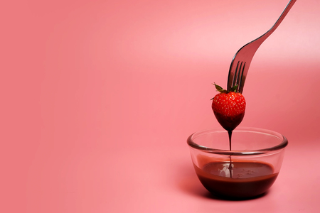 fondue strawberry soaked in hot black chocolate on a fork with pink background with minimalist style .have some spec for write wordingの写真素材