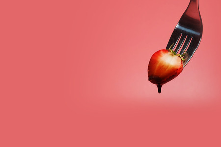 fondue strawberry soaked in hot black chocolate on a fork with pink background with minimalist style .have some spec for write wordingの写真素材