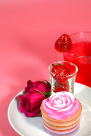 thai dessert sweet layered jelly cake  rose flower topping design Served with strawberry and decorate with pink red rose with romantic pink tone backgroundの写真素材