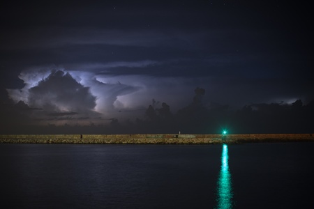 Green beacon over water against the storm skyの写真素材