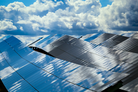 Silicon panels of solar batteries against the cloudy sky in the middle of the day.