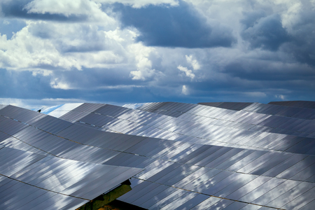 Silicon panels of solar batteries against the cloudy sky in the middle of the day.