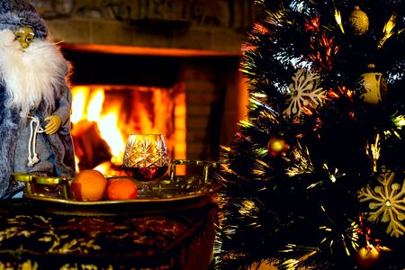 On New Year's Eve by the burning fireplace. Christmas. Joyful anticipation of the holiday in the warmth and surrounded by Christmas attributes.の写真素材