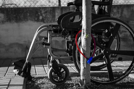 Wheelchair attached to a tree with an anti-theft lock. You won't need it anymore! Let it stand here.