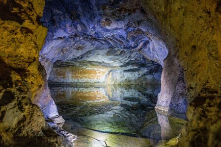 A cave with colorful walls and a tank full of water.