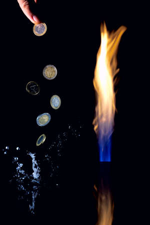 A gas flare devouring money. Gas money. Pillar of fire and levitating Euro coins. A splash of water flying around.の写真素材