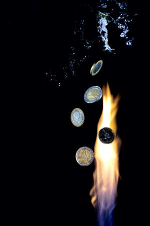 A gas flare devouring money. Gas money. Pillar of fire and levitating Euro coins. A splash of water flying around.の写真素材