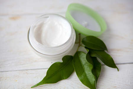 Cosmetic cream with flowers and spa stones on wooden backgroundの写真素材