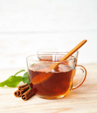 Glass cup of black tea with cinnamon sticks on a  wooden table.の写真素材