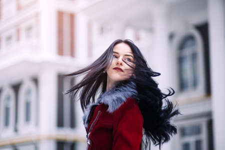 Young beautiful model in the city.Dynamically Beautiful brunette woman walks down the street.Hair fluttering in the wind.の写真素材