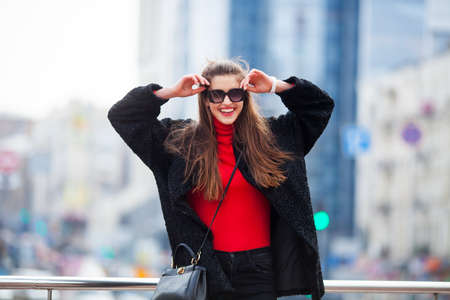 Outdoor lifestyle close up portrait of happy young woman in stylish casual outfit portrait on the street.Pretty hipster girl having fun and enjoying holidays On the background of the big city.の写真素材