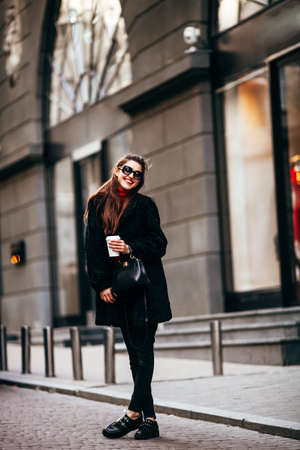 Outdoor fashion portrait of stylish young woman having fun, emotional face , laughing, looking at camera. Urban city street style. Spring or fall outfitの写真素材