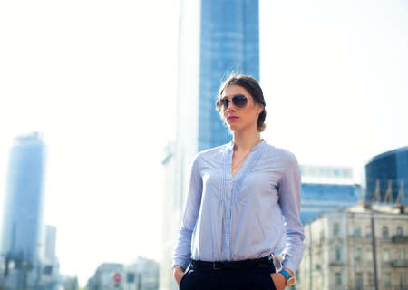 Portrait of successful businesswoman in blue shirt and sunglasses in big city Pleasant woman manager.の写真素材