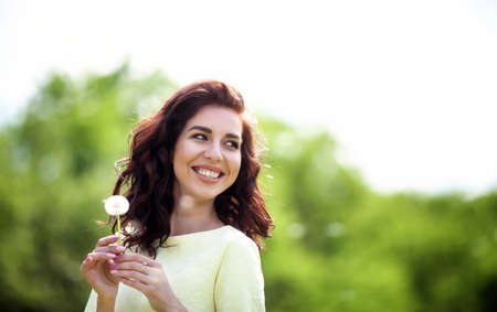 pretty girl relaxing outdoor, having fun, holding plant, Beautiful charming girl's smiling. happy young lady and spring green nature, harmony conceptの写真素材
