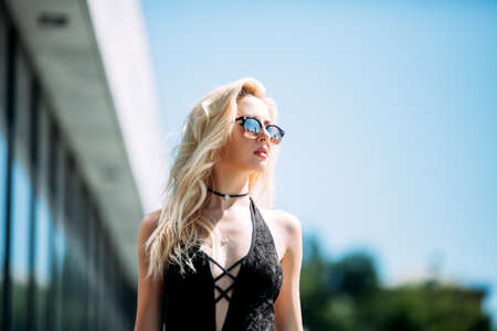 Female fashion concept. Outdoor waist up portrait of young beautiful woman posing on old street. Model wearing stylish clothes, looking at camera. Sunny day. City lifestyle. Copy, empty space for textの写真素材