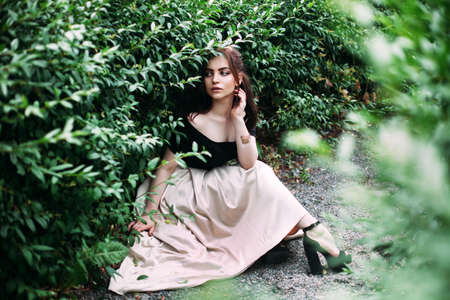 Beautiful brunette woman in a long dress in the summer garden Fashion style beauty romantic portrait of young pretty beautiful woman Stunning girl looking down.Closeupの写真素材