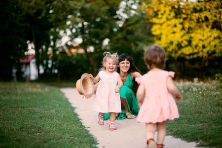 Young beautiful mother playing and hugging with her daughters on the nature outdoors. space for textの写真素材