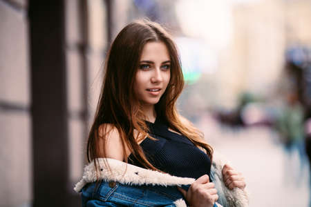 Amazing joyful pretty girl with long brunette hair. posing outdoor. denim jacket,brunette hair Close up fashion street style portrait Abstract looking to the side. Concept of street fashionの写真素材