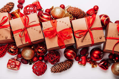 Christmas decorations and gifts on a white background. Cones, balls of red and gold beige gifts decorated with red ribbon Clouse upの写真素材