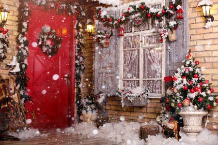 Christmas decor on a patio. Doors are decorated by a festive chaplet and toys. Fir-tree at a window, snowの写真素材