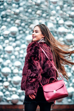 Outdoor close up portrait of young beautiful girl with long hair young girl Dynamically walking down the street. Hair trembles in the wind.の写真素材