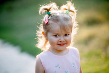 Happy funny girl enjoying the rain Cute little toddler girl standing on the nature outdoors Close up portrait of Pretty little girl in the parkの写真素材