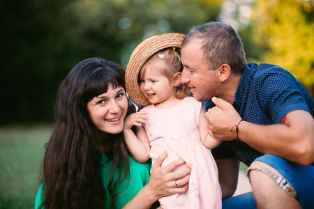 family, child and happiness concept - hugging mother and daughter and father Close up portrait