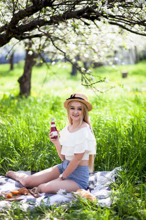 girl is sitting on the lawn. girl at picnic. woman in a straw hat. picnic in the fresh air Lovely girl with long hair resting at outdoor in sunny morning.の写真素材
