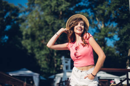 Closeup portrait of effective girl with long curly hair smiling to camera having fun on the beach, dancing and smiling, vacation mood.Nice laughing girl in hat.の写真素材