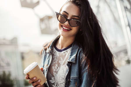 Happy attractive young woman in sunglasses walking in the city. Dressed in stylish clothes. close-up portrait of a young sexy girl hipster.の写真素材
