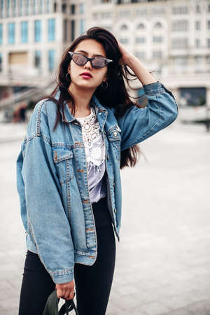 Interested glamorous woman in oversized denim jacket makes selfi. Gorgeous brunette girl posing on...