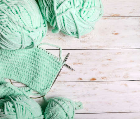 Skeins of wool and knitting needles on a wooden background.