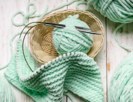 home hobbies, cozy knitted plaid with a ball of yarn in the living room on a wooden backgroundの写真素材