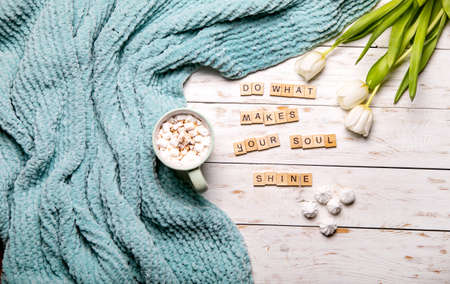 Turquoise plaid cup of cocoa decorated with marshmallows, white tulips. Positive postcard....