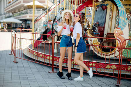 Closeup fashion lifestyle portrait of two pretty best friends girls, wearing bright swag style hats, mirrored sunglasses, having fun and make crazy funny faces. Two sisters posing on partyの写真素材