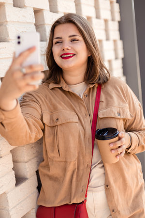 Young beautiful plus size girl is video chatting on the phone of the street.