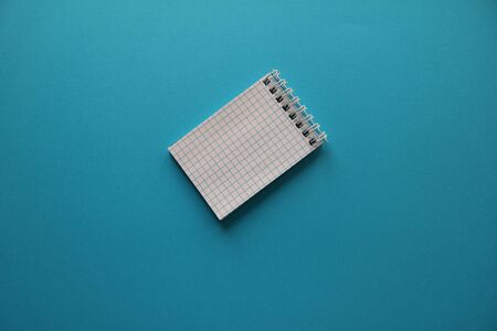 checkered notebook lies on a blue backgroundの写真素材