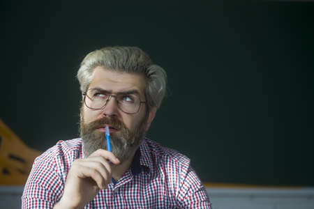 Portrait of thoughtful senior caucasian man with a grey beard and holding pen.の写真素材