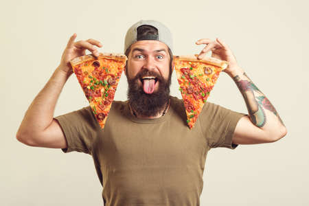 Portrait of a handsome man eating a slice of pizza margherita.の写真素材