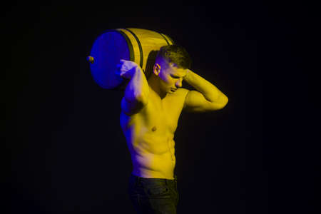 Muscular worker shirtless holding big blue barrel over his head.の写真素材