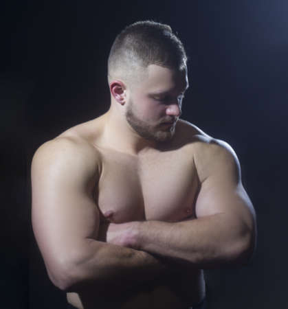 Strong athletic man fitness model torso showing big muscles over black background.の写真素材