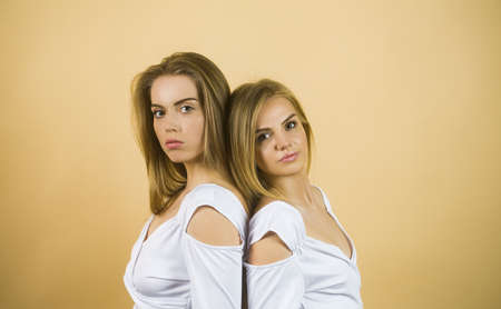 Gorgeous two caucasian sisters models posing together on beige background, smiling.の写真素材