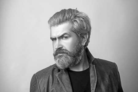 Attractive young bearded man in a brown leather jacket pose in studio.