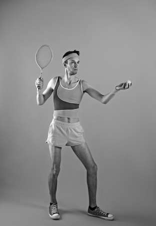 Funny playful young man tennis player with racket imitating ball serve. black and white.の写真素材