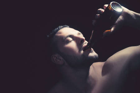 Close up of a strong man drinking a bottle of beer.の写真素材