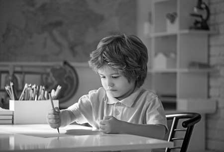 Smiling little boy drawing in the room.