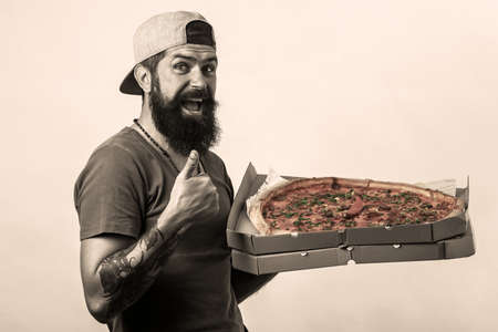 Pizza delivery man with work uniform picking up pizza in box with thumbs up because something good has happened.の写真素材