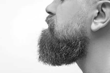 Perfect beard. Close-up of young bearded man standing against gray background.