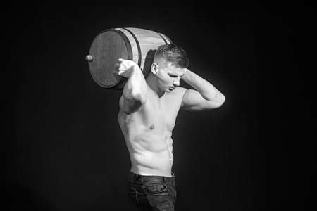 Muscular worker shirtless holding big blue barrel over his head.の写真素材
